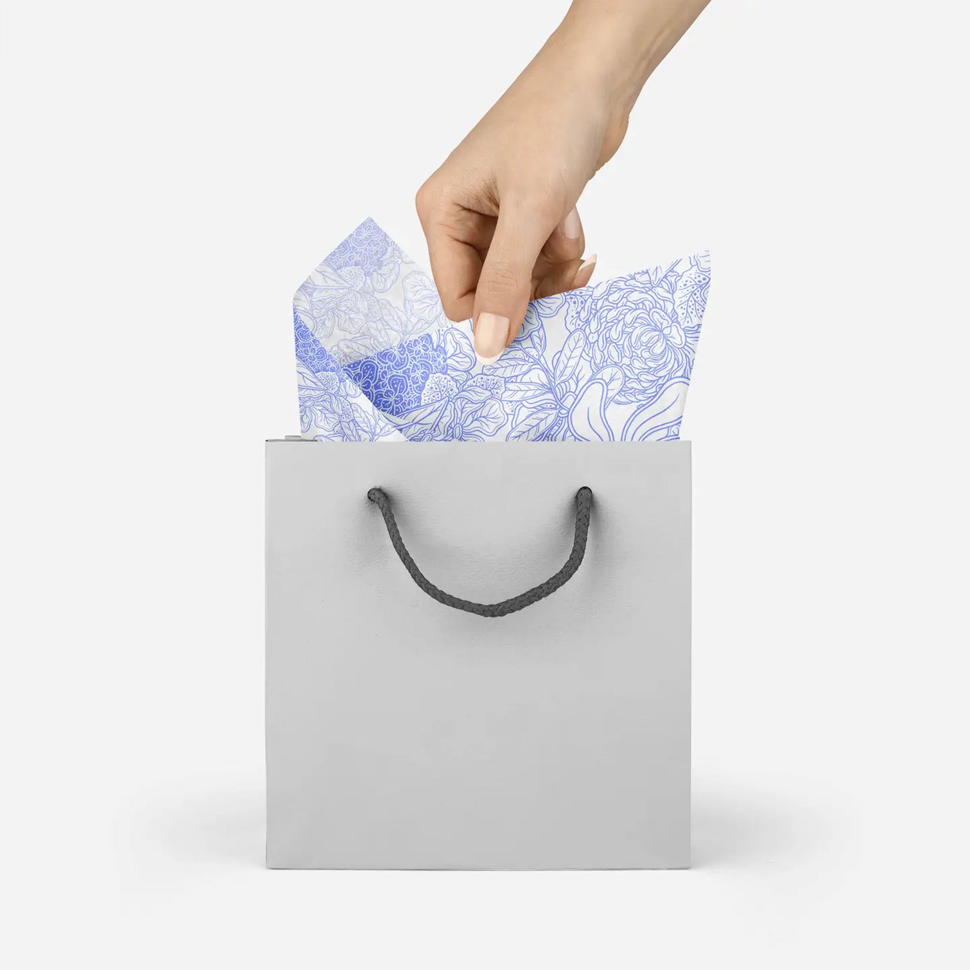 Model pulling white and lavender floral tissue paper out of white gift bag