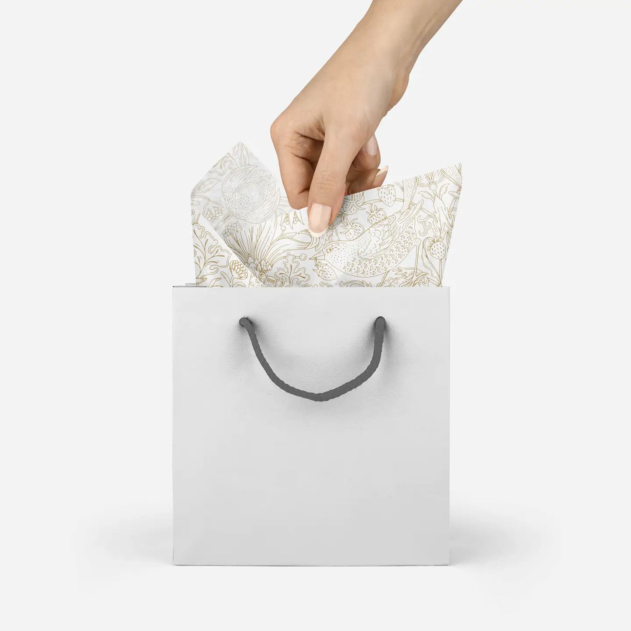 model pulling decorative tissue paper with gold floral pattern out of a silver gift bag