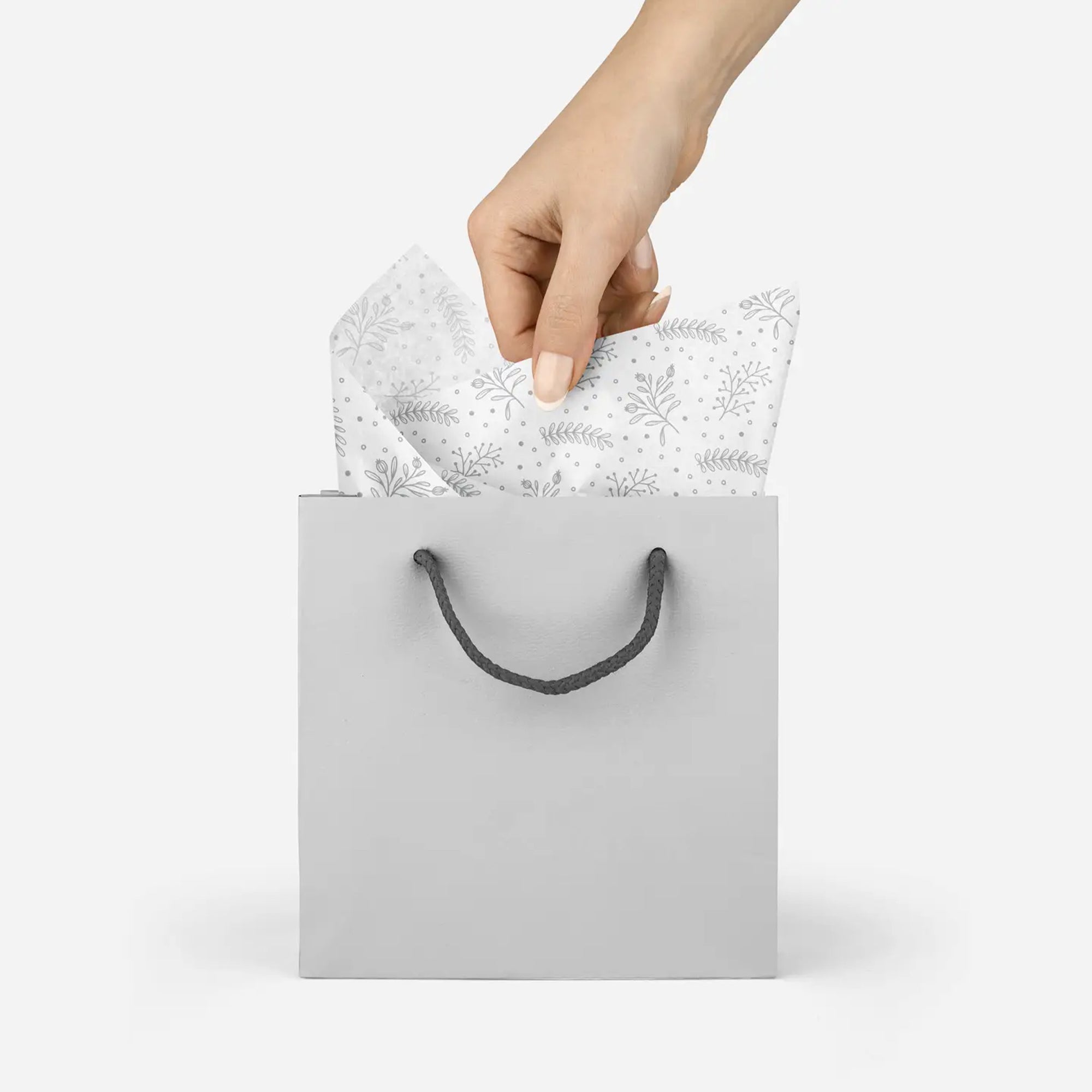 Model pulling silver floral patterned tissue paper out of a silver bag