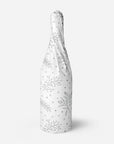 Silver floral patterned tissue paper wrapped around a bottle
