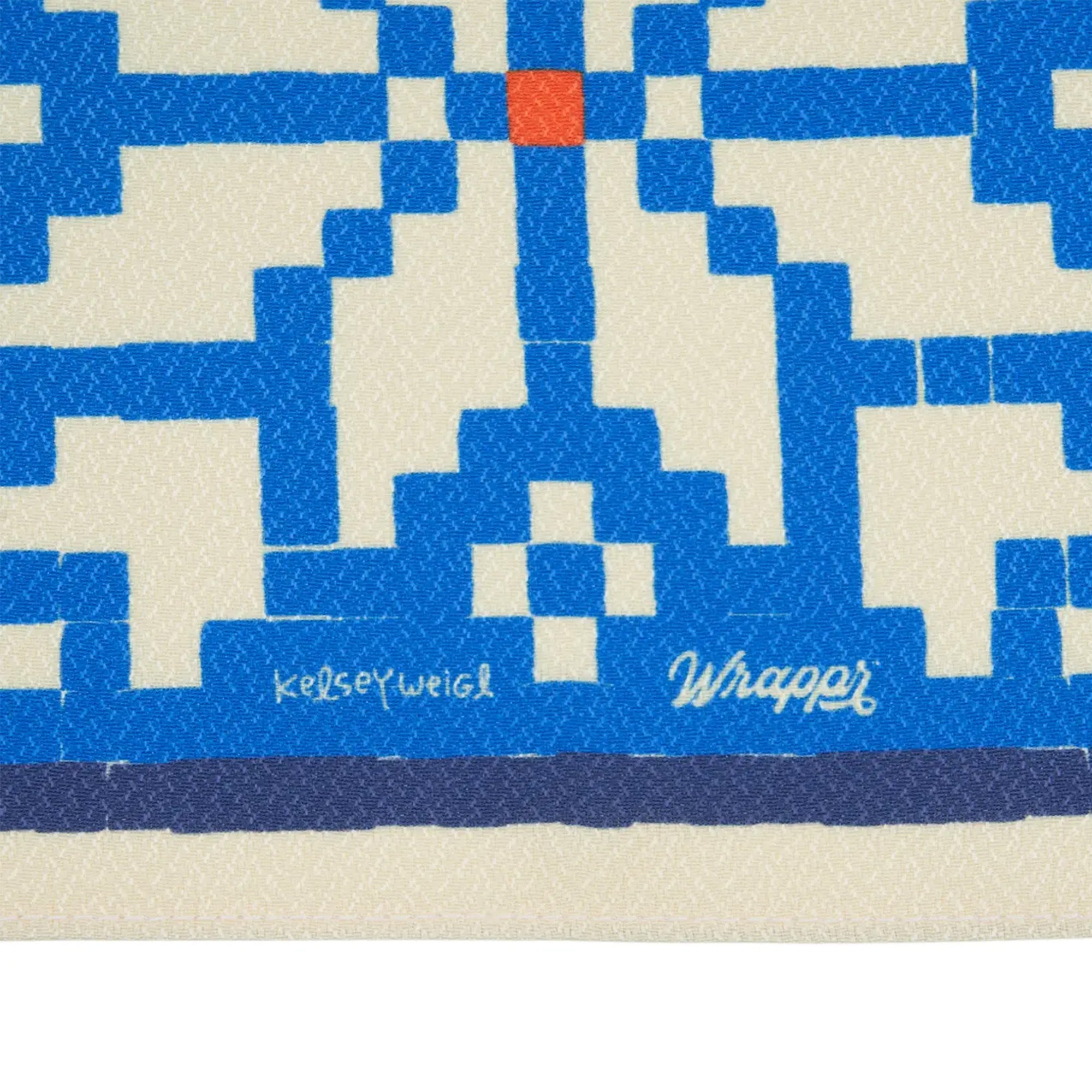 Close-up of a woven mat with blue and beige pattern, featuring the brand 'Kelsey Weigl'.