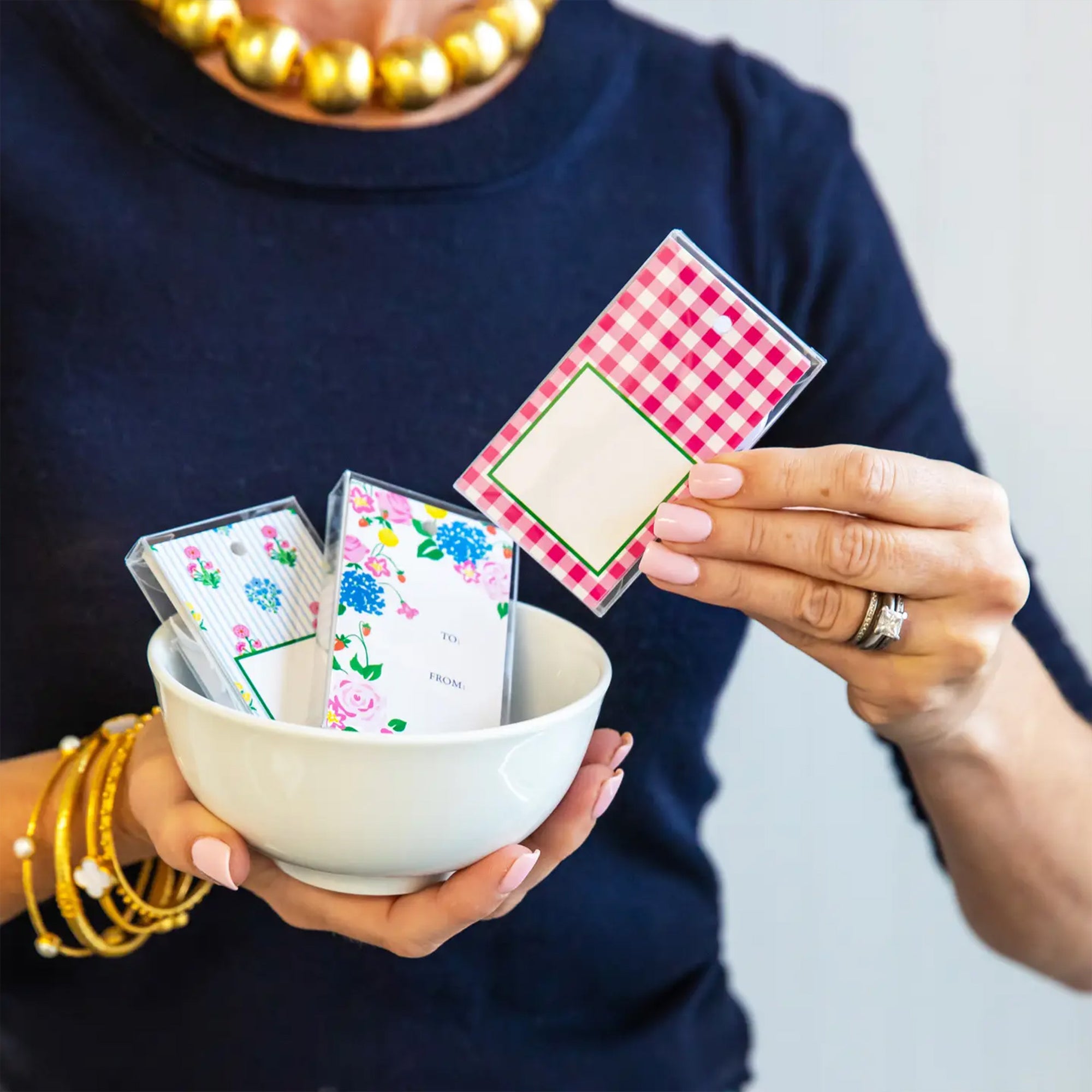 Person holding a bowl with playing cards and a deck of cards on a plain background
