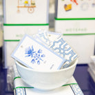 White bowl with blue floral and geometric designs on cards against a blurred store background