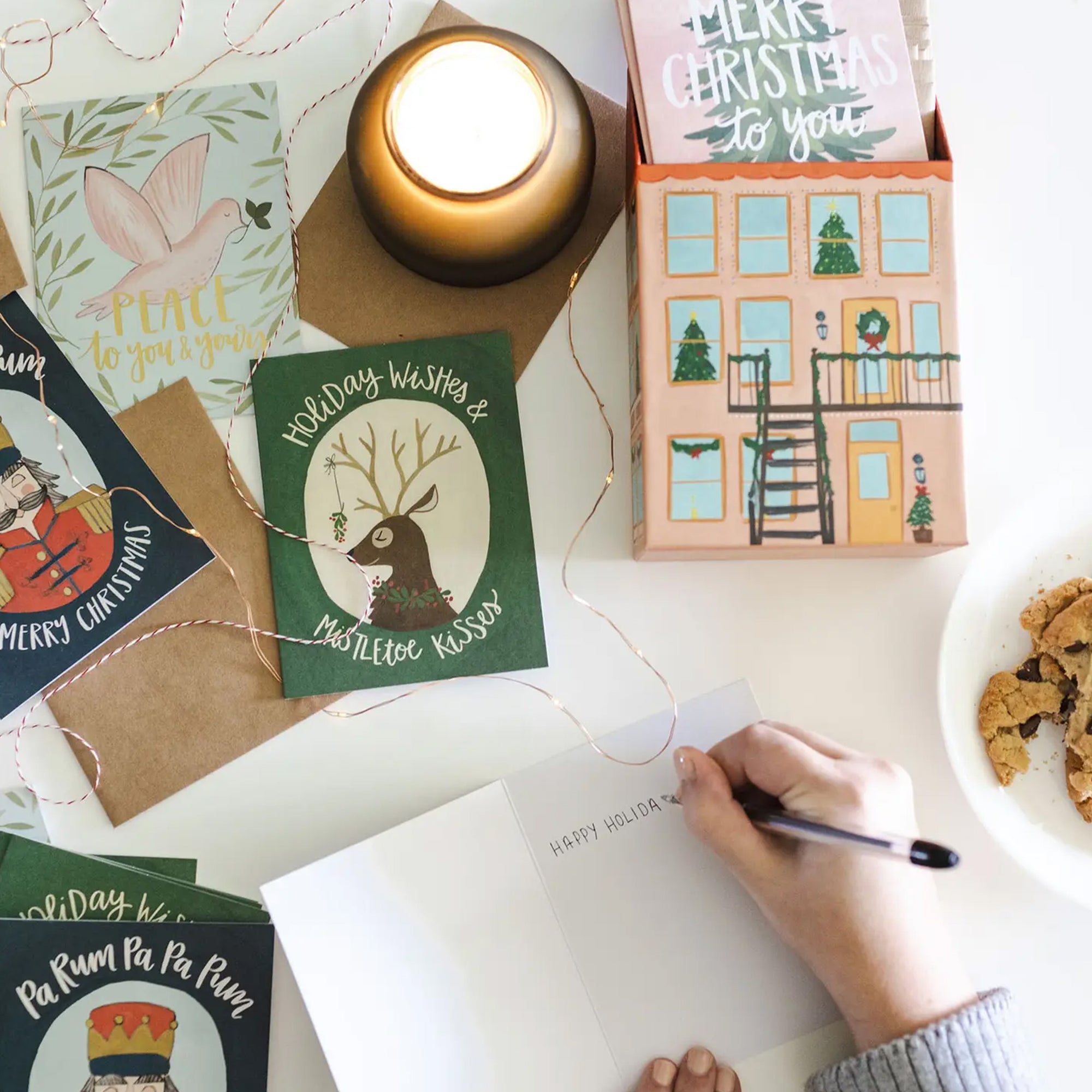 Handwriting on a card with Christmas cards and a candle in the background