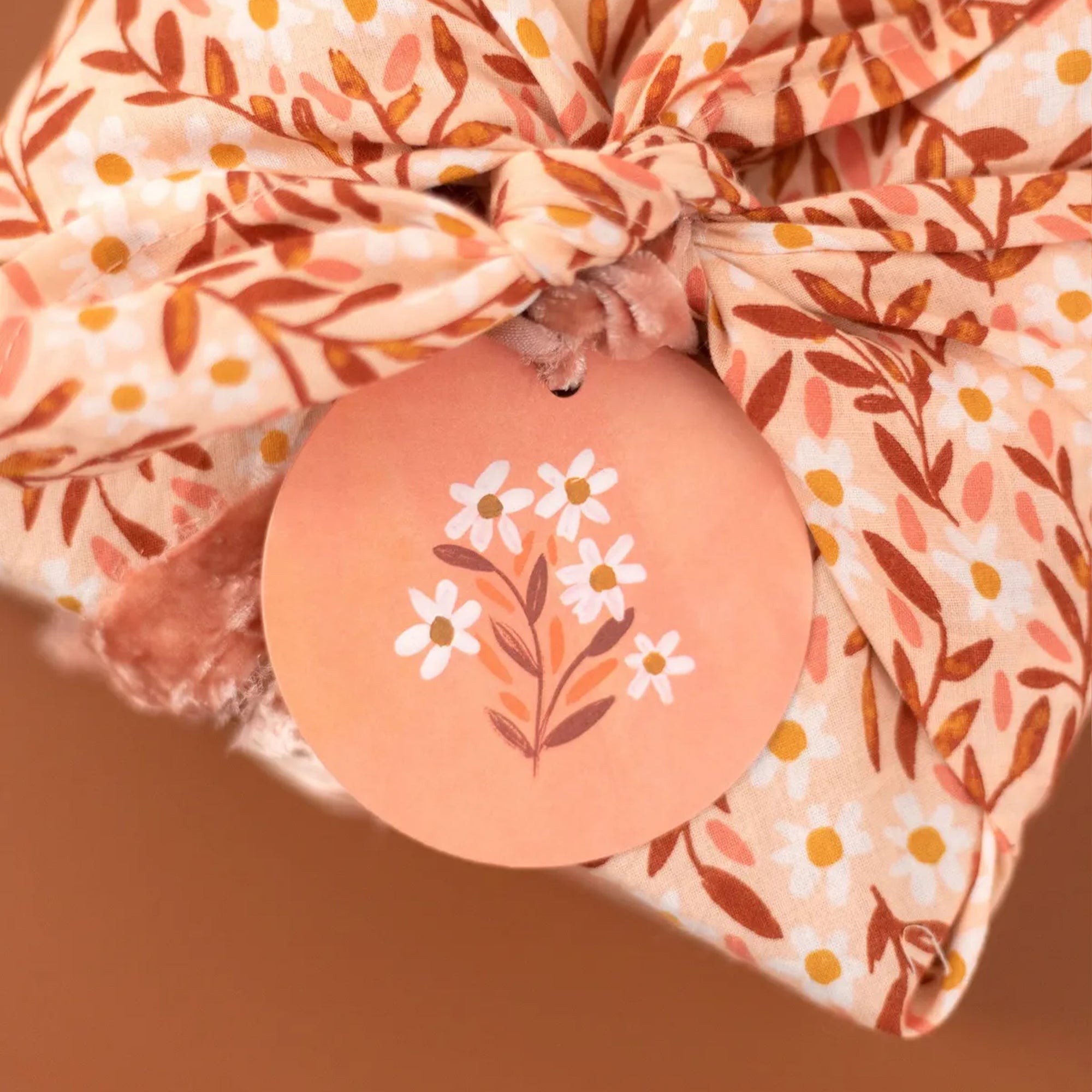 Floral-patterned fabric with a decorative tag featuring floral design on a brown background