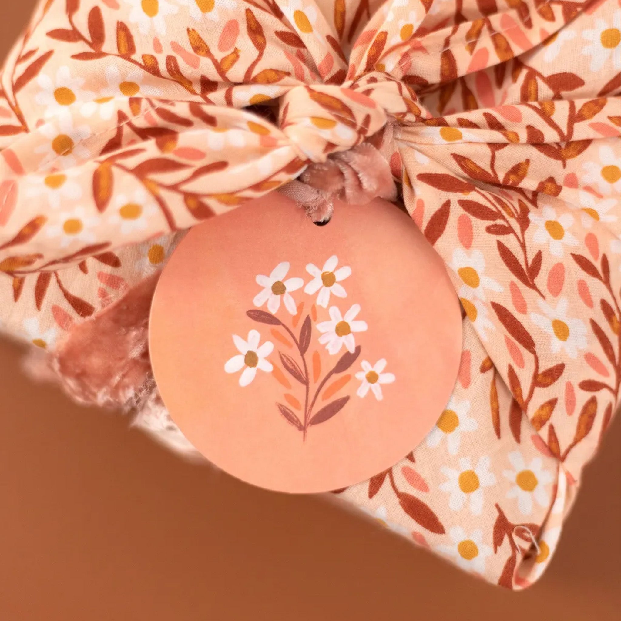 Floral-patterned fabric with a decorative tag featuring floral design on a brown background