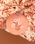 Floral-patterned fabric with a decorative tag featuring floral design on a brown background