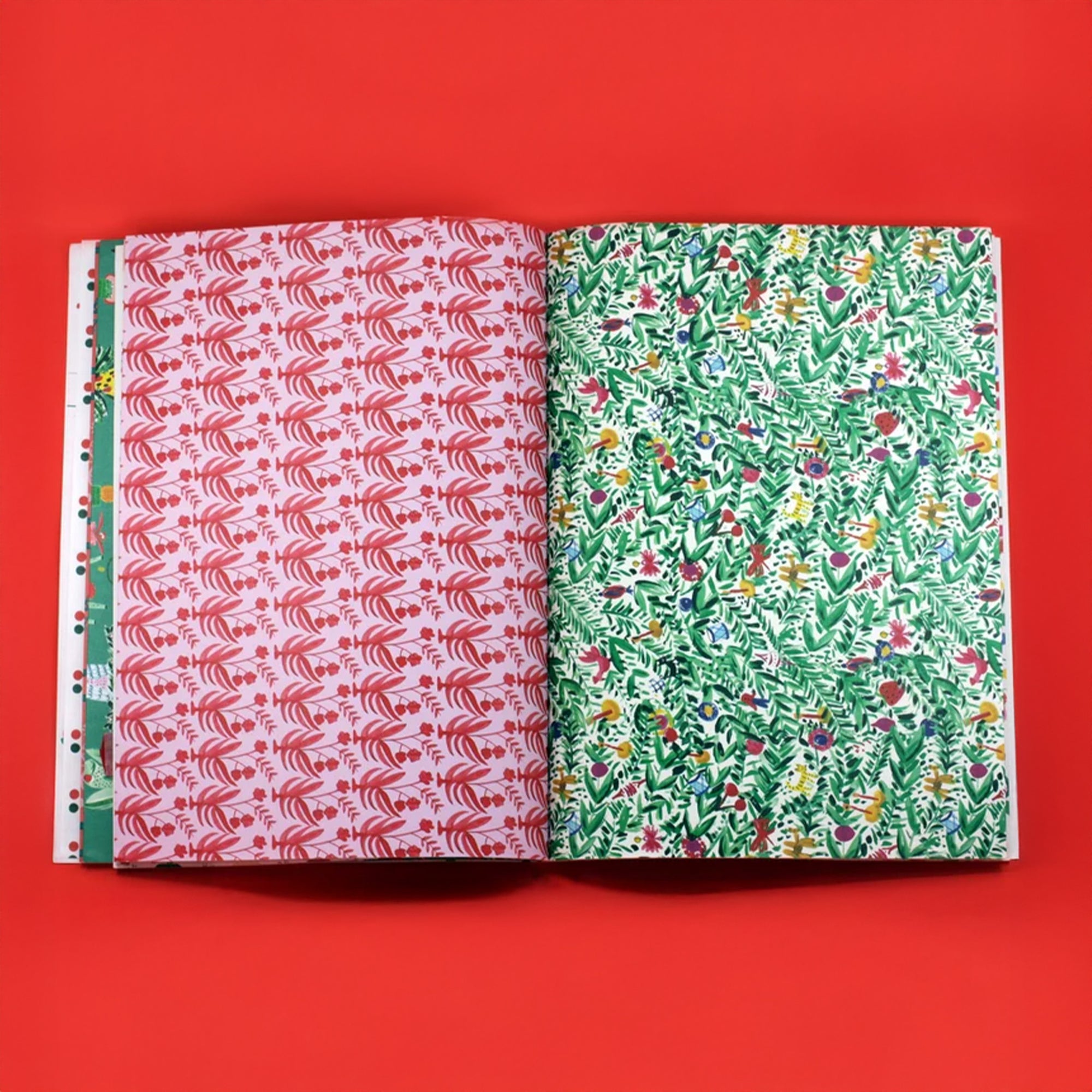 Two patterned books open to display red and green Two wrapping paper pages on a red background