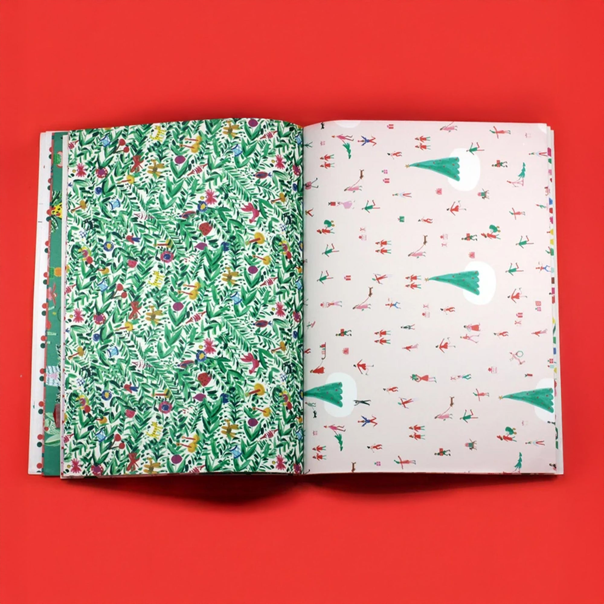 Two sheets of wrapping paper pages, one green with floral design and one white with tree design, on a red background.