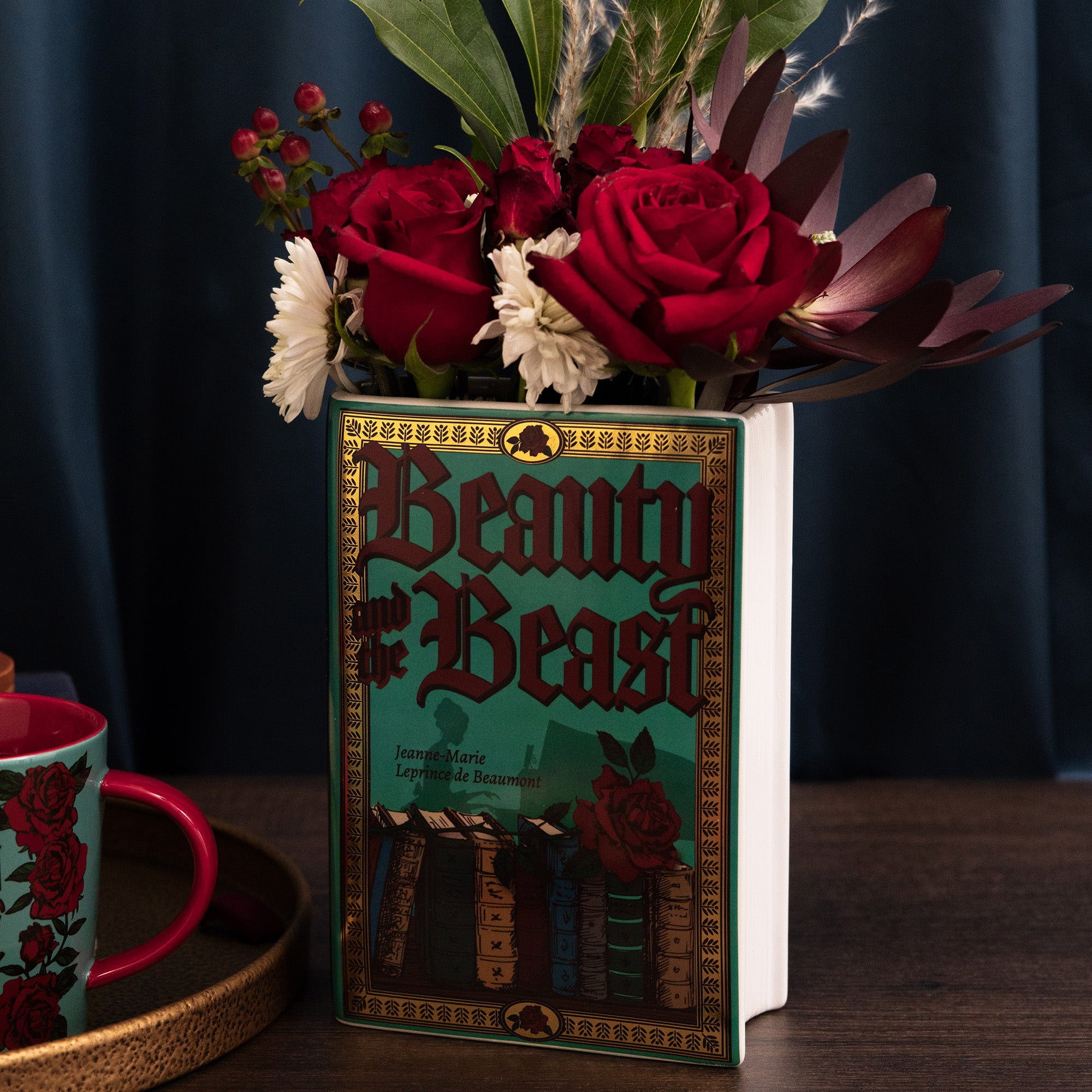 teal beauty and the beast book shaped vase with flowers inside