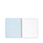 An open spiral-bound notebook with a light blue left page and white lined right page, photographed on a plain white background.