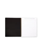A black spiral-bound notebook shown open, with a blank black cover on the left and lined white pages on the right, photographed on a clean white background.