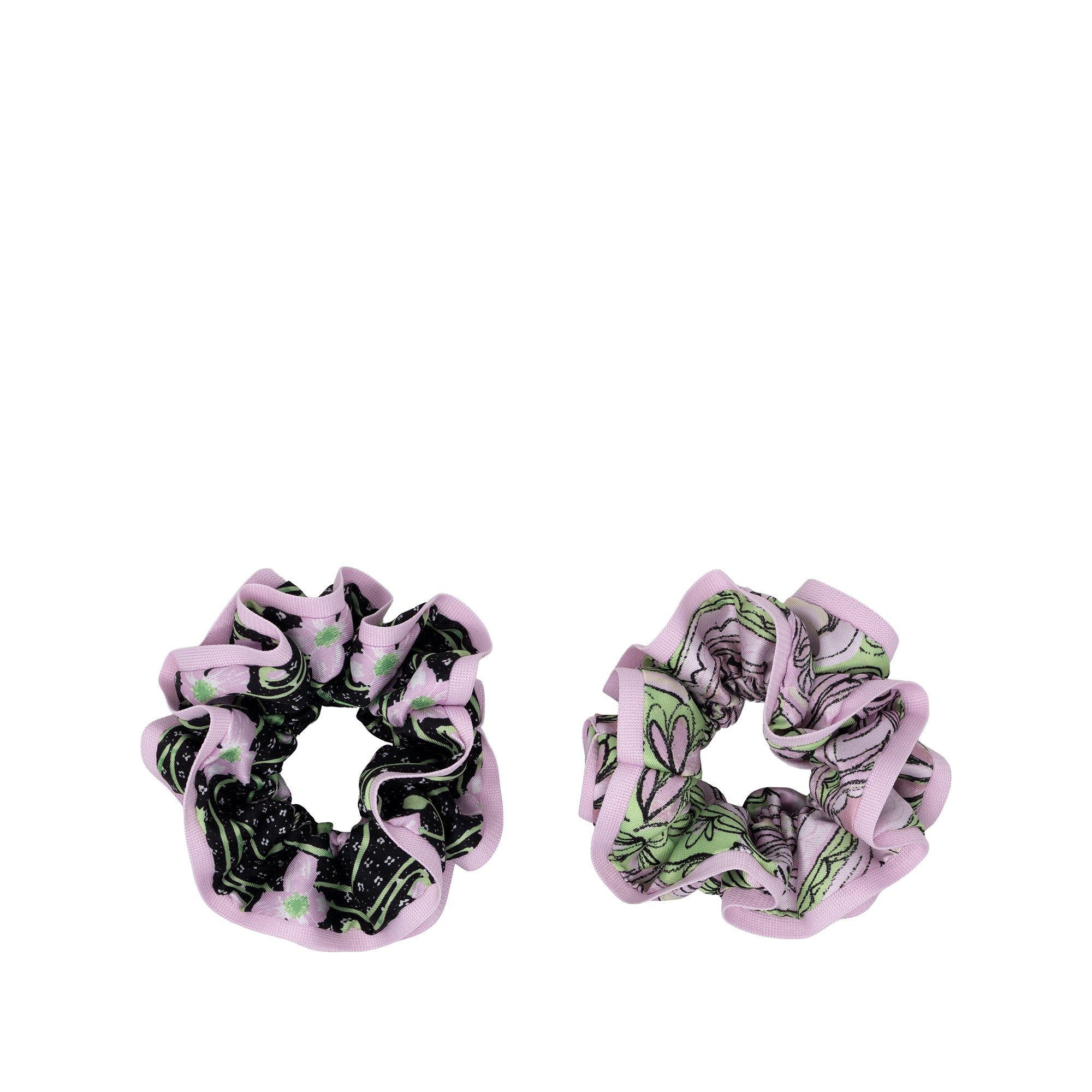 Two fabric hair scrunchies on a plain white background. One scrunchie has a black and green botanical pattern with light pink ruffled edges, and the other has a green floral pattern with light pink ruffled edges.