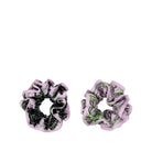 Two fabric hair scrunchies on a plain white background. One scrunchie has a black and green botanical pattern with light pink ruffled edges, and the other has a green floral pattern with light pink ruffled edges.
