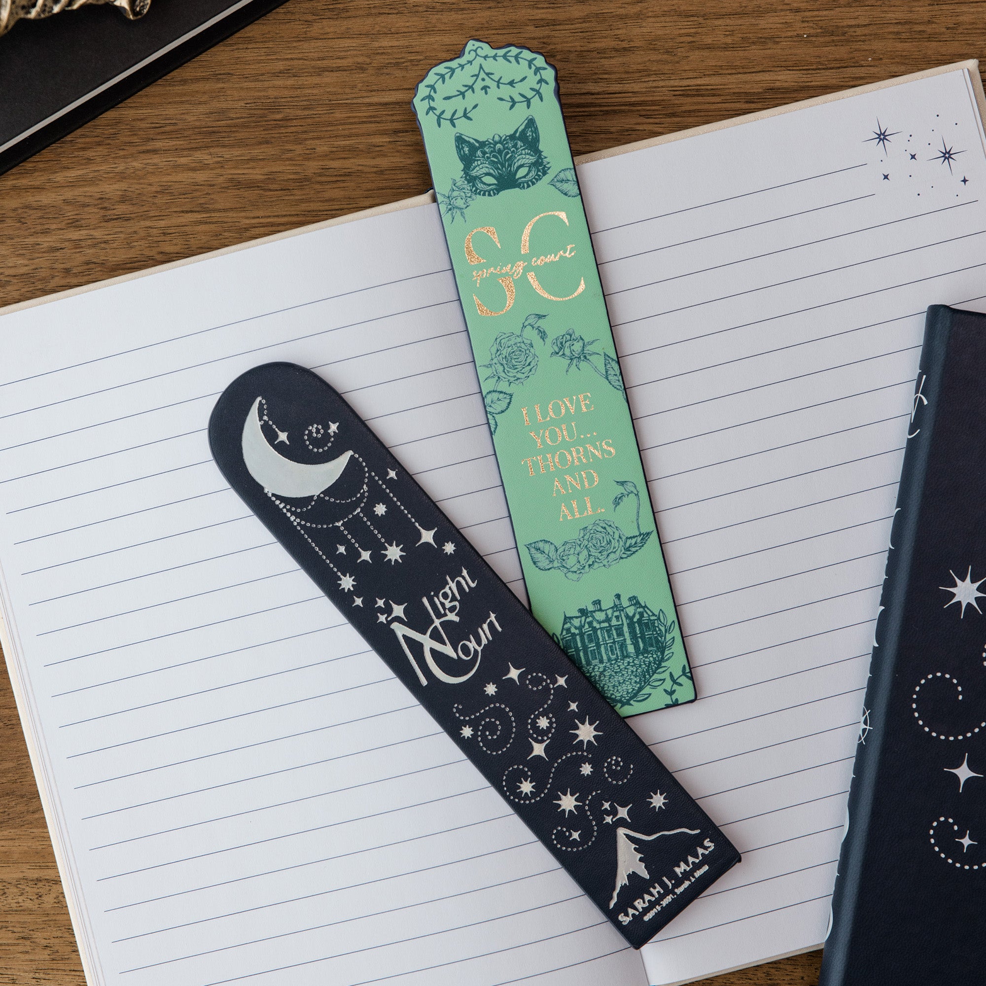 Two decorative bookmarks on a notebook with Spring and Night Court designs.