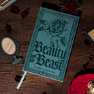 Teal notebook with rose design and 'Beauty and the Beast' text on a white background