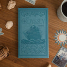 Blue book titled 'The Odyssey' by Homer on a wooden surface with decorative items.