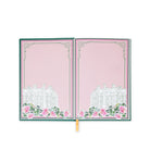 Open notebook with pink cover featuring a white building and floral design on a white background