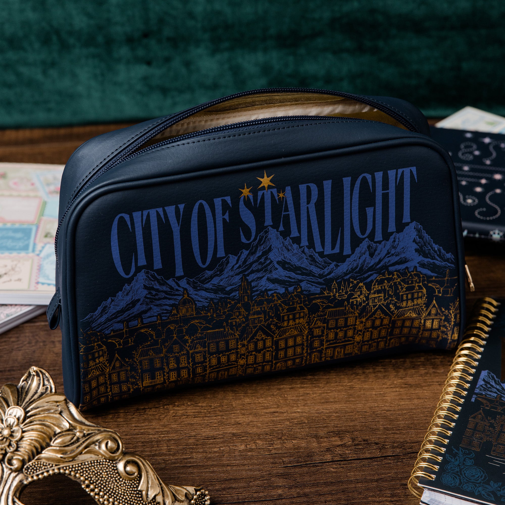Navy blue pouch with 'City of Starlight' design on a wooden surface
