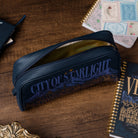 Blue case with 'City of Starlight' text on a wooden surface with books.