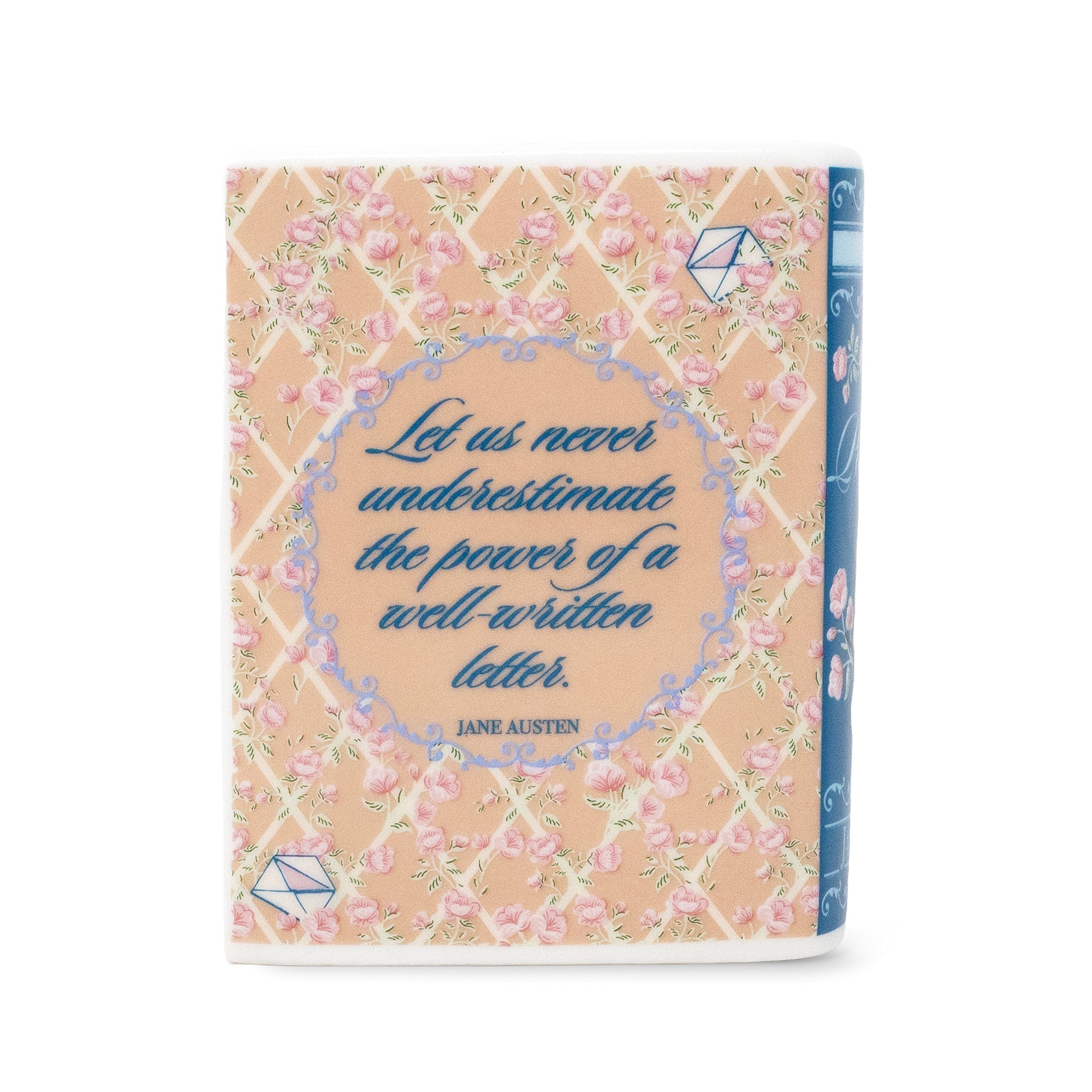 A decorative book or notebook cover shown upright on a white background, featuring a peach floral lattice pattern, blue script text reading 'Let us never underestimate the power of a well-written letter. JANE AUSTEN,' and a blue spine edge visible on the right.