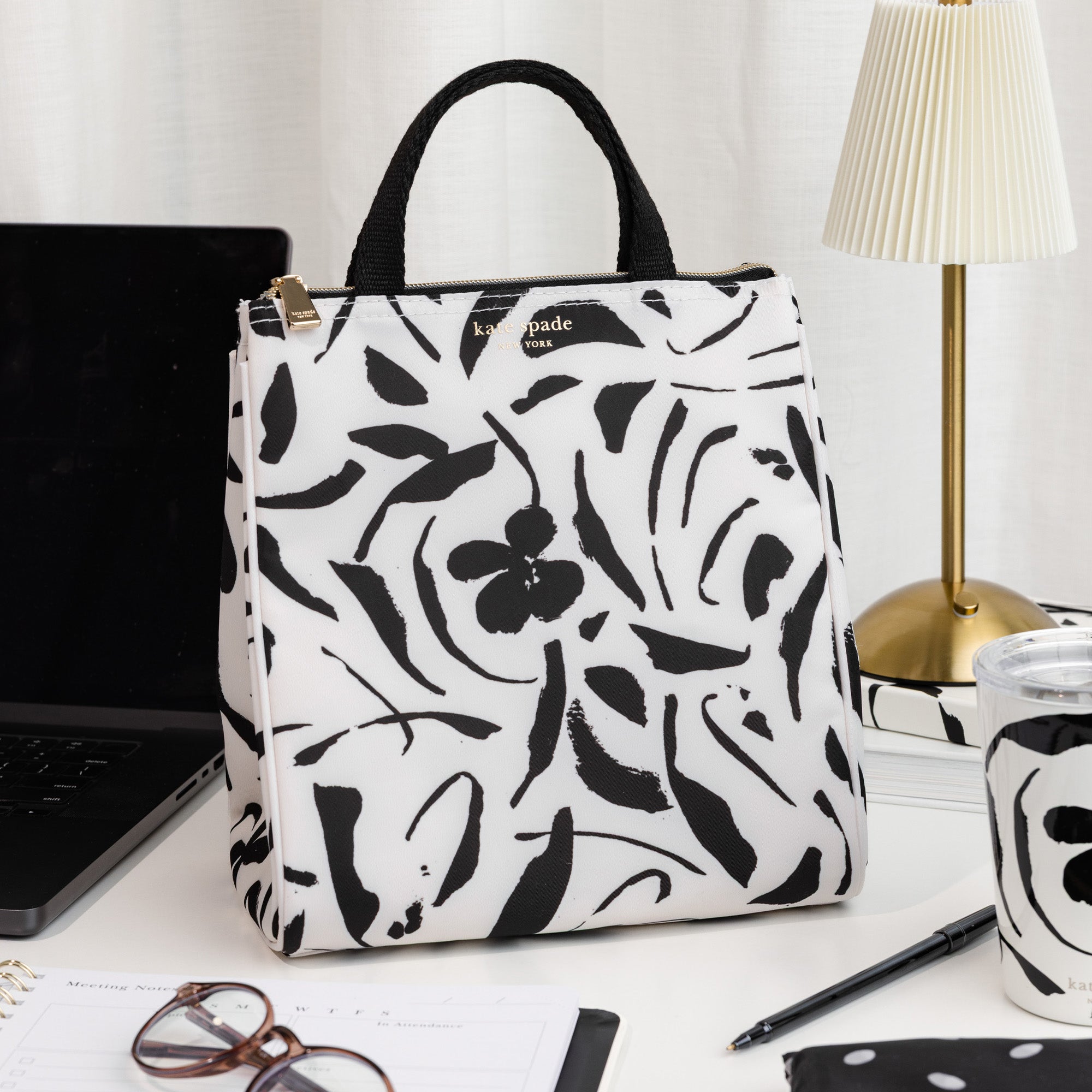 Floral patterned lunch bag on a desk with a laptop and other items.