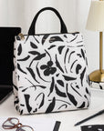 Floral patterned lunch bag on a desk with a laptop and other items.