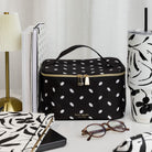 Black polka dot lunch bag with 'kate spade' branding on a white surface with decorative items.