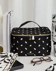 Black polka dot lunch bag with 'kate spade' branding on a white surface with decorative items.