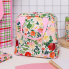 Floral-patterned bag with pink handle on a white surface