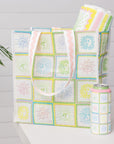 Tote bag, blanket, and can cooler with pastel pattern on a light gray background