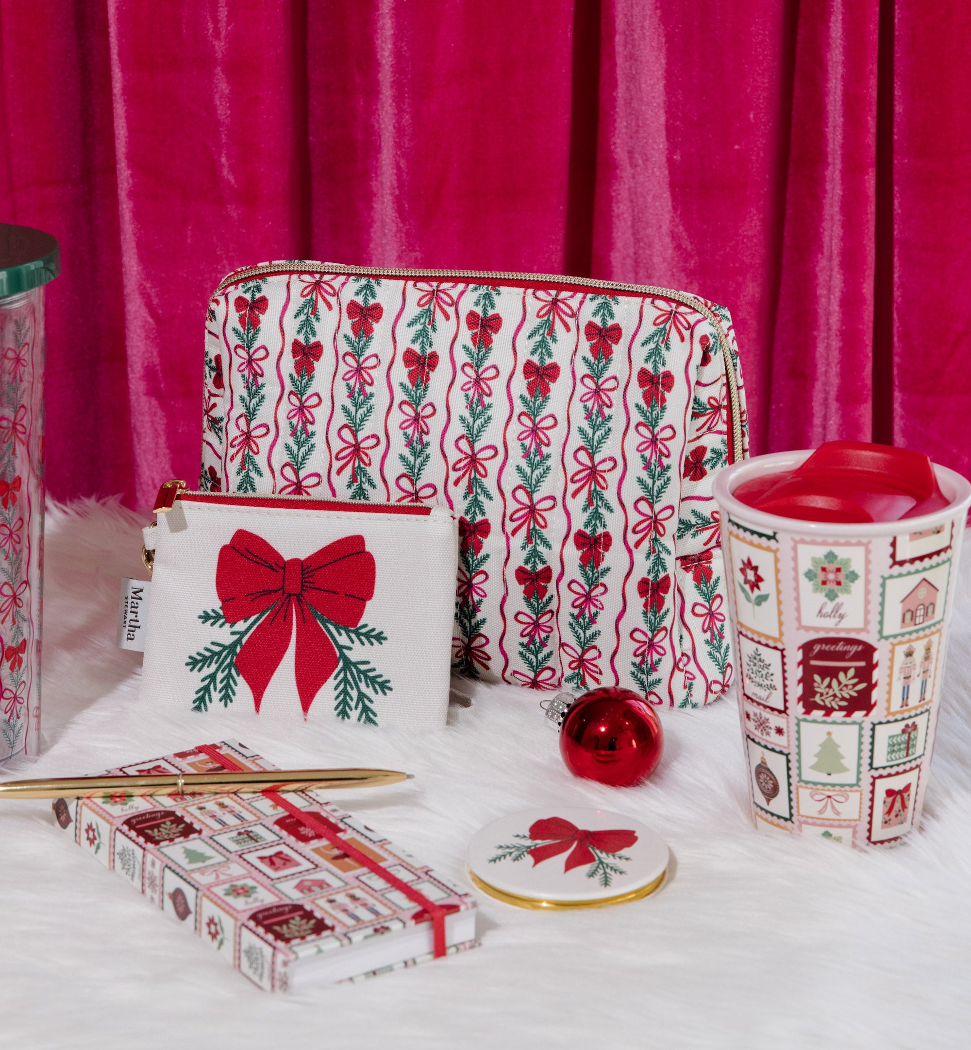 Holiday-themed products including a pouch, tumbler, and a notepad against a pink curtain background.
