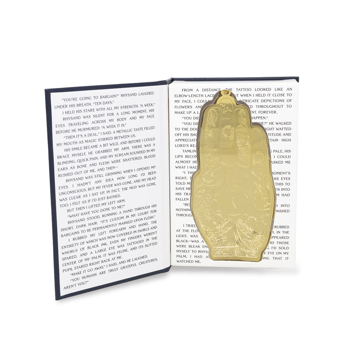A gold-toned metal hand, displayed on an open book with printed text.