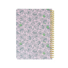 Notebook with floral pattern and gold coil binding on a white background