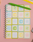 Notebook with sun tile on a pink surface with stationery items.