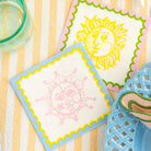 Two decorative napkins with sun designs on a striped surface.