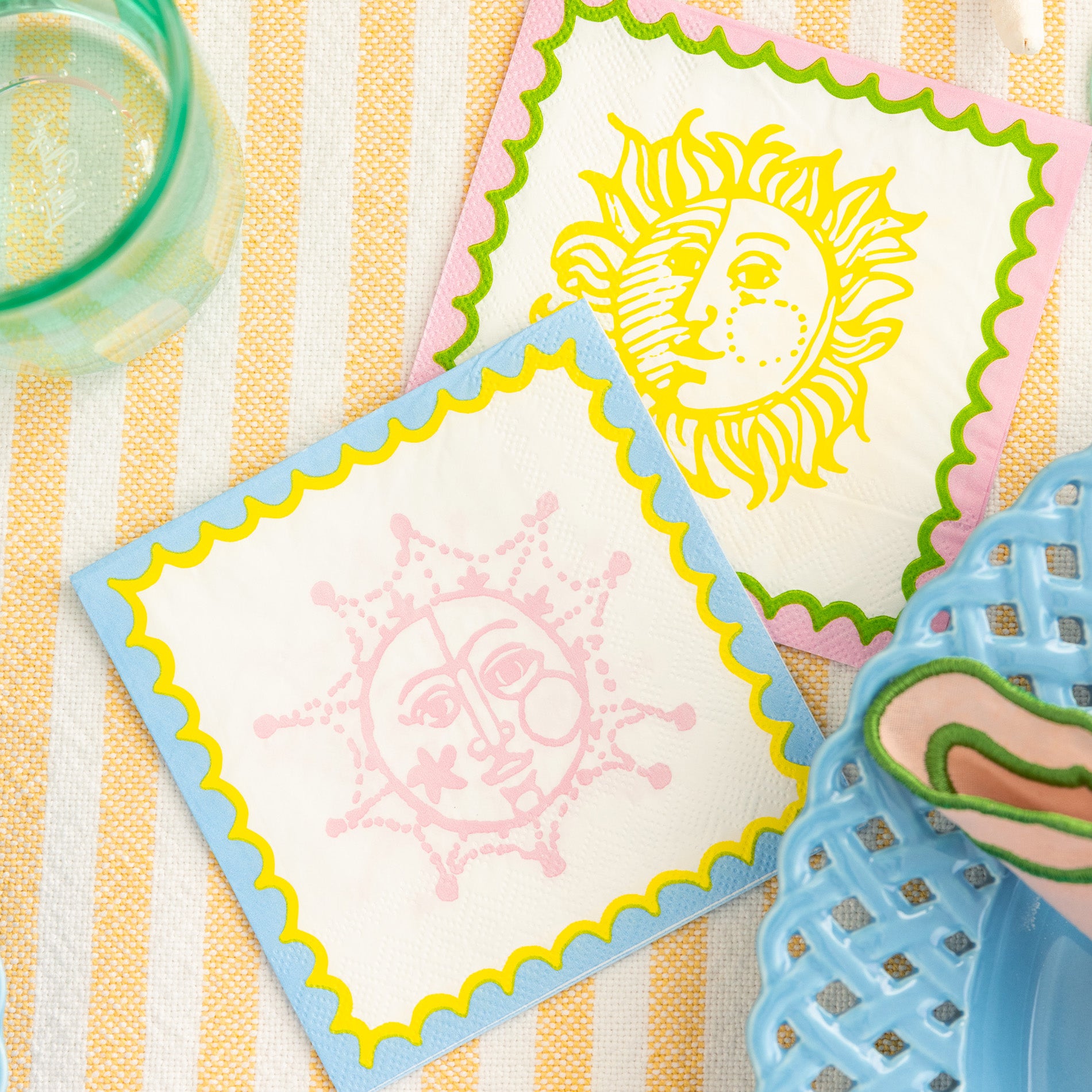 Two decorative napkins with sun designs on a striped surface.