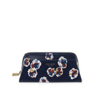 A navy blue zip-around cosmetic pouch by Kate Spade New York, decorated with a pattern of colorful abstract flowers in red, blue, yellow, and white, with a gold-tone zipper pull.