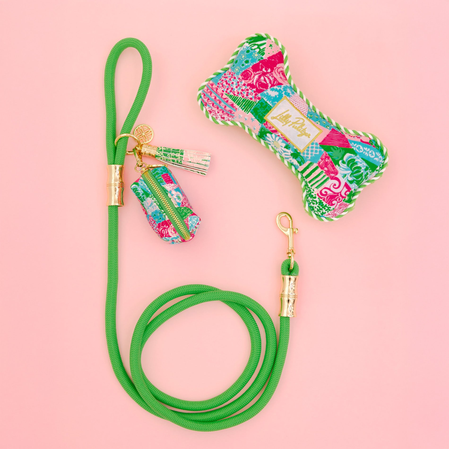 Green dog leash with floral patterned bag and keychain on a pink background