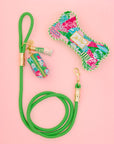 Green dog leash with floral patterned bag and keychain on a pink background
