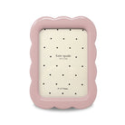 Pink photo frame with scalloped edges and 'kate spade new york' branding on a white background.