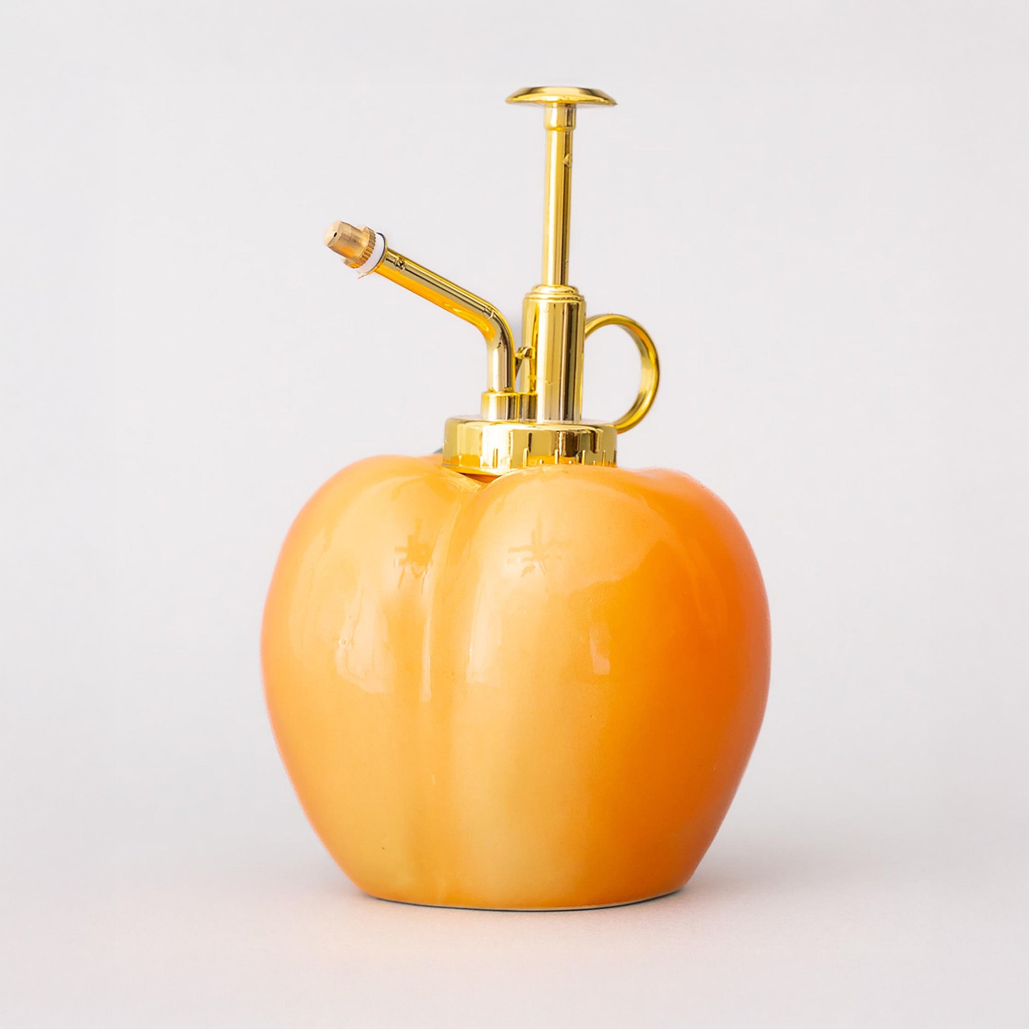 Back view of Peach-shaped bottle with gold nozzle on a white background