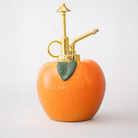 Peach-shaped bottle with gold nozzle on a white background