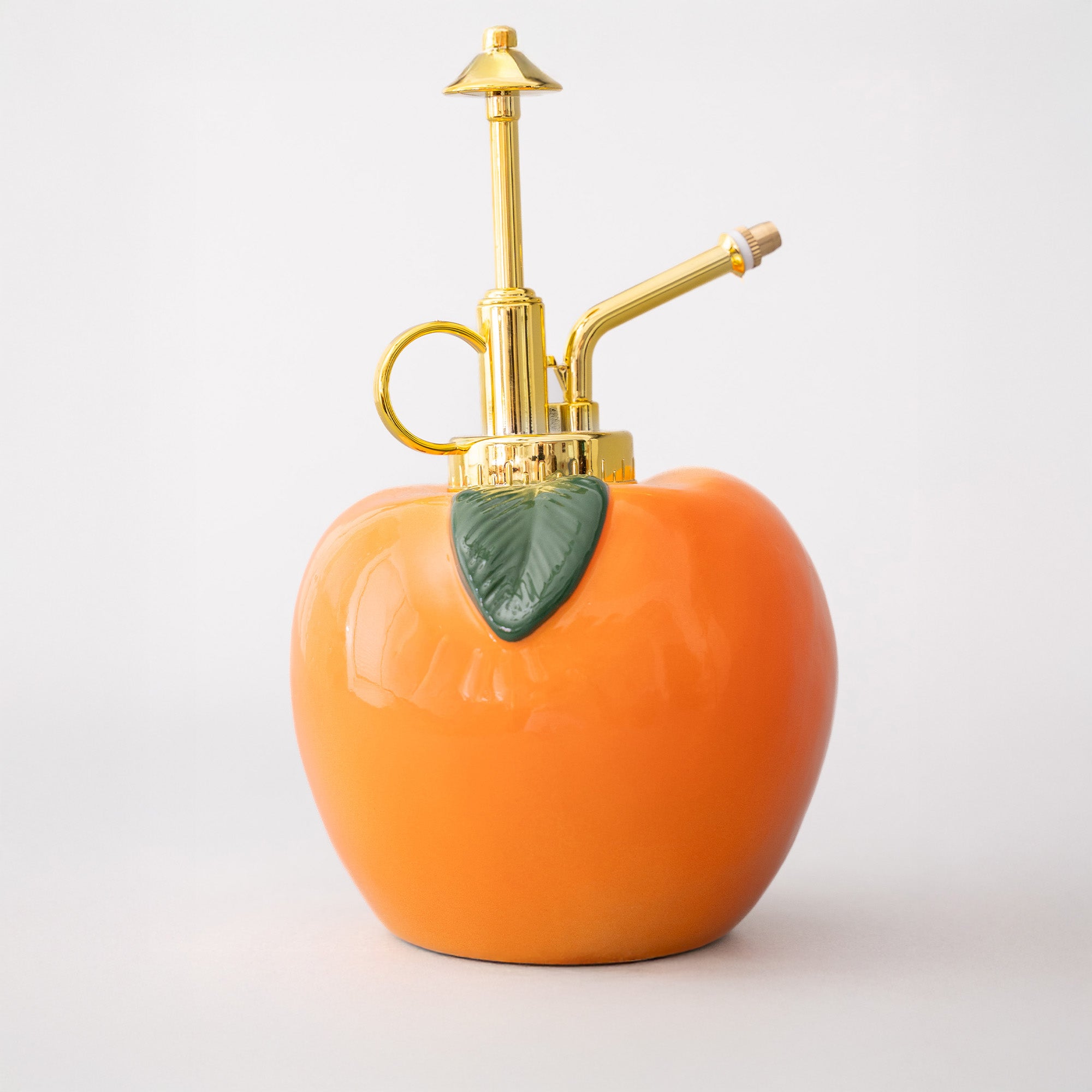 Peach-shaped bottle with gold nozzle on a white background