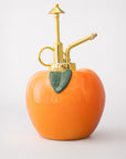 Peach-shaped bottle with gold nozzle on a white background
