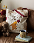 Tote bag with Winnie the Pooh design on a couch next to a teddy bear and a cup of coffee.