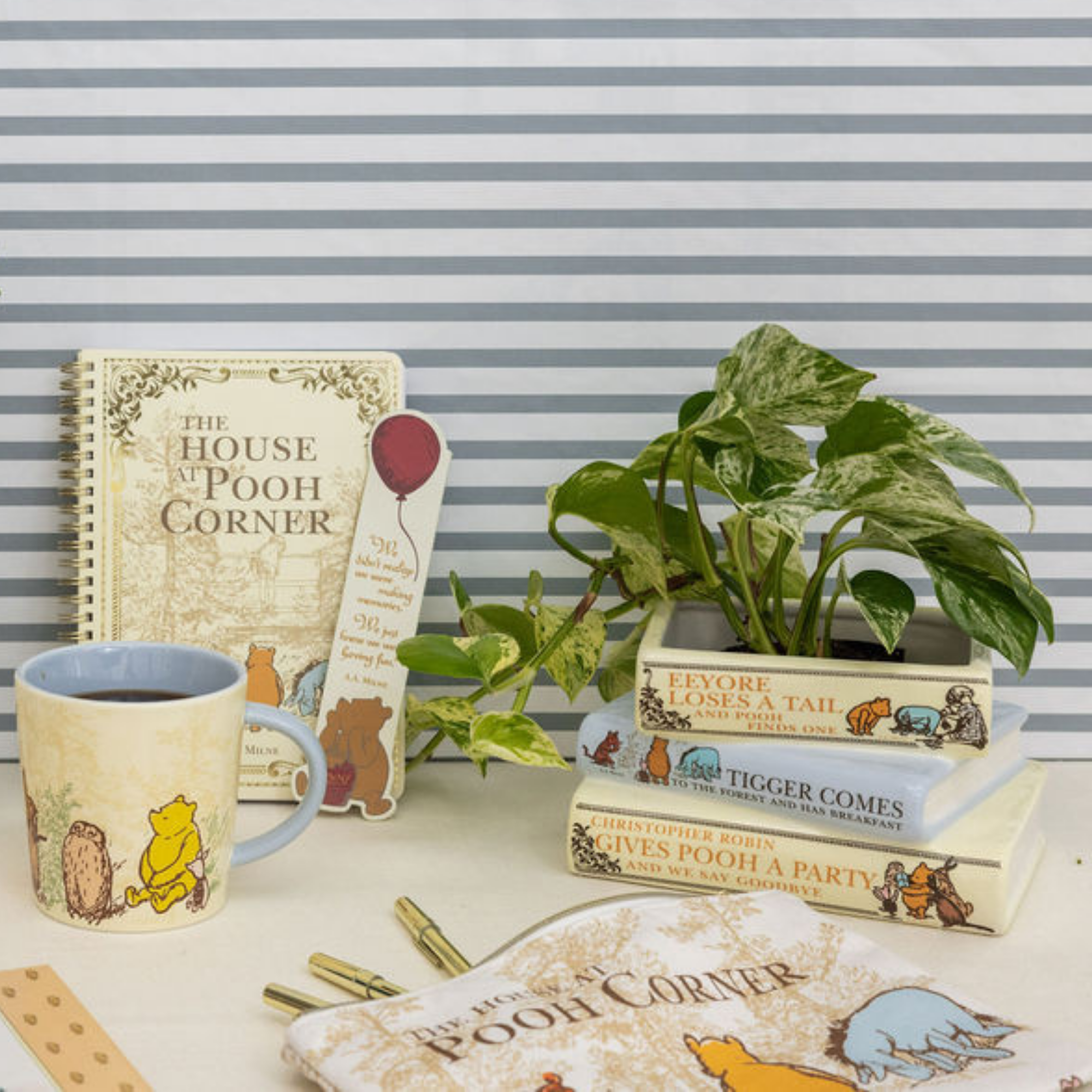 Winnie the Pooh-themed items including a mug, books, and a plant on a striped background