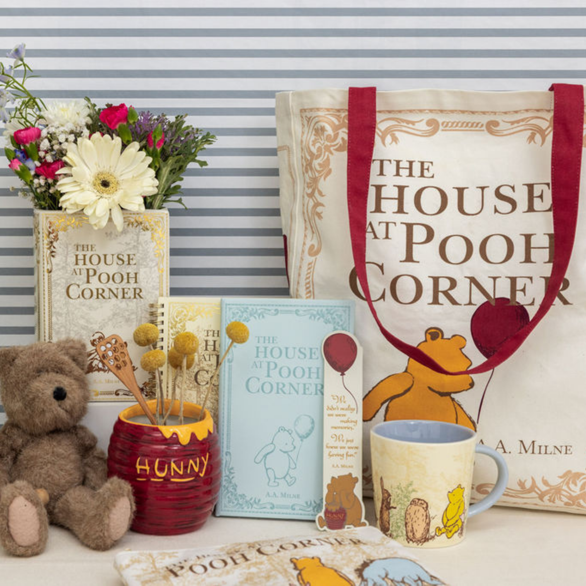 Collection of 'The House at Pooh Corner' themed items including a teddy bear, mug, and tote bag.