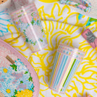 Two colorful cups, one with floral design and the other with striped pattern, on a colorful background.