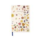 A notebook with a cream-colored cover decorated with various whimsical illustrations such as a sun, flamingo, flowers, and tools, featuring the text 'COLLECT YOUR THOUGHTS' and a blue ribbon bookmark.